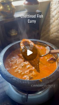 a bowl filled with soup sitting on top of a stove next to a wooden spoon