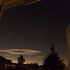 the night sky is lit up with stars and clouds in the distance, as seen from an apartment window