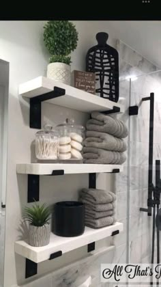 bathroom shelves with towels, candles and plants on them in black and white decorating