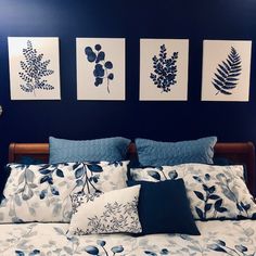 a bed with blue and white sheets, pillows and pictures on the wall above it