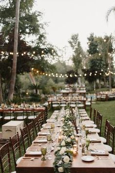 a long table set up with place settings and candles for an outdoor wedding reception at dusk