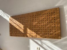 a wooden wall hanging on the side of a white wall next to a bed in a room