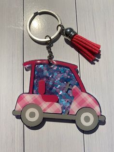 a pink car shaped keychain with a tassel hanging from it