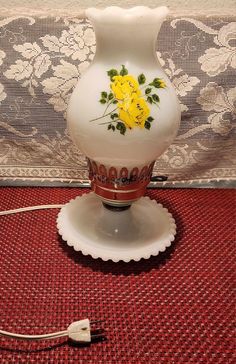 a white vase sitting on top of a table next to a red and white rug