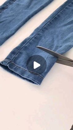 someone is cutting the jeans with scissors on top of it and another pair of scissors in front of them