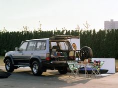 an suv is parked next to a table and chairs