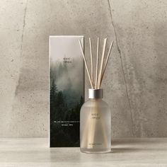 reeds in a glass bottle next to a box with an image on it and a book