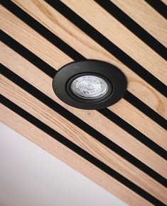 a close up of a light on a wooden ceiling with black lines in the background