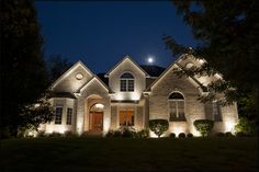 a house lit up at night with lights on the front and side of the house