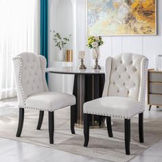 two white chairs sitting next to each other near a table