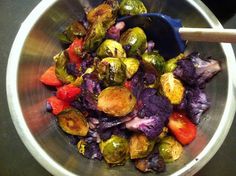 a metal bowl filled with brussel sprouts and tomatoes