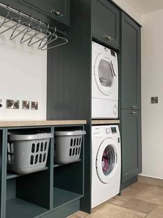 a washer and dryer in a laundry room next to cabinets with hanging hooks