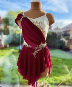 a woman's red and white dress on display in front of a building with grass