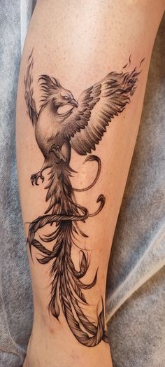 a tattoo on the leg of a woman with a bird flying above her head and an arrow