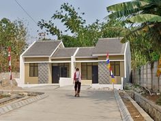 a man walking in front of two small buildings with flags on each side of them