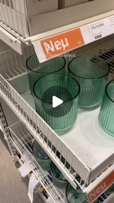 green glass cups are stacked on top of each other in a store display case for sale