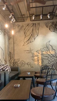 the interior of a restaurant with tables, chairs and couches in front of a floral wall mural