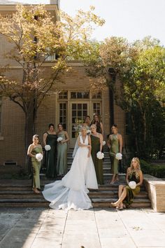 a group of women standing around each other in front of a building with flowers on the steps