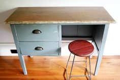 an old desk with two stools and a wooden table top that has been painted blue