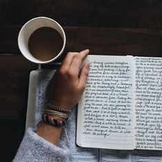 a person is reading a book and holding a cup of coffee