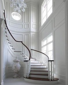 an elegant staircase with chandelier and white walls