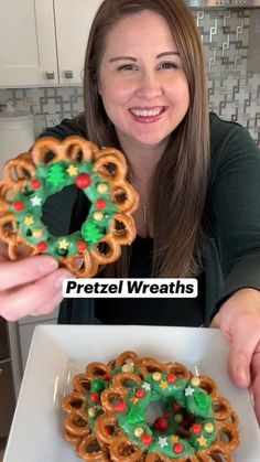 a woman holding up a pretzel wreath on top of a white square plate