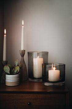 three candles sitting on top of a table next to a vase with succulents