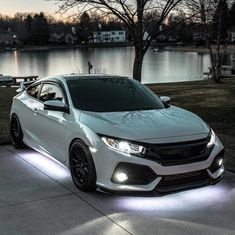 a white car parked in front of a lake