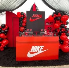 a display with balloons and nike logo on it's side, in front of a backdrop