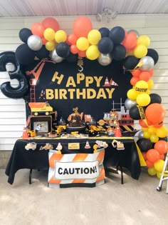 a construction themed birthday party with balloons and decorations on the outside wall, including an orange black and white theme