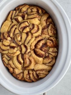 an apple pie is in a white crock pot on the table top, ready to be eaten