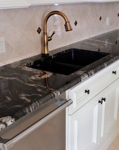 a kitchen with marble counter tops and stainless steel dishwasher in the center, along with white cabinets