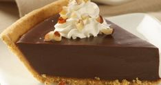 a piece of chocolate pie with whipped cream and nuts on top is sitting on a plate