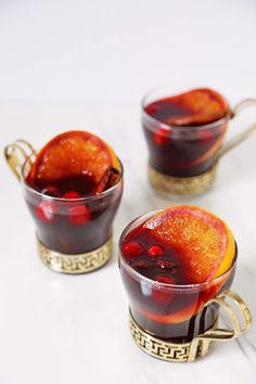 two glasses filled with red liquid on top of a white table