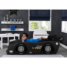 a young boy laying in a race car bed