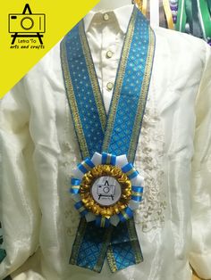 a white shirt with blue and gold ribbons on it's lapel that has an award in the center