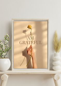 a person holding a flower with the words i am grateful on it in front of a wall