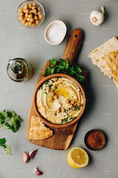 hummus and pita chips on a cutting board with olives, parsley