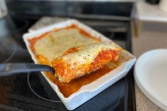 a white plate topped with lasagna covered in sauce