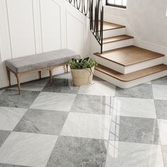 a white and black checkered floor in a house with stairs, potted plant and bench