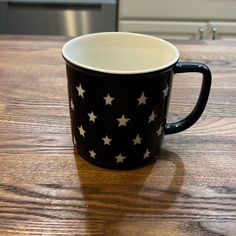 a black and white coffee cup sitting on top of a wooden table