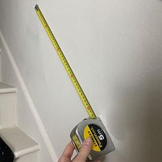 someone is measuring the wall with a tape and a ruler on top of their hand