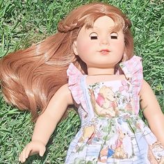 a doll laying on the grass with her hair blowing in the wind and eyes closed