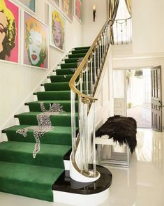 a staircase with green carpet and pictures on the wall