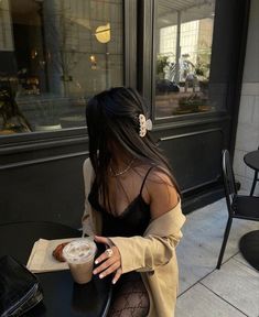 a woman sitting at a table with a cup of coffee