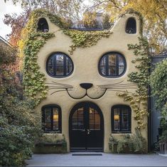 a cat shaped house with ivy growing all over it's face and windows on the side