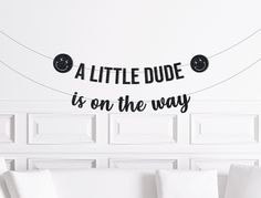 a little dude is on the way sign hanging from a string in a living room