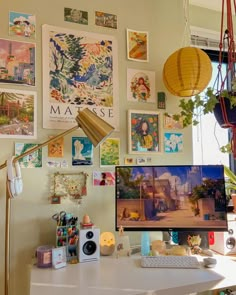 a desk with a computer and various pictures on the wall