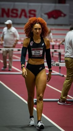 a woman with red hair walking on a track