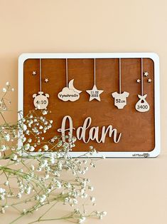 a wooden sign that says adam hanging on the wall next to some baby's breath flowers